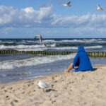 Mann sitzt am Ostseestrand